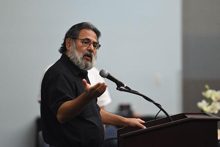 Professor in glasses speaking into microphone at lectern